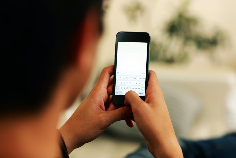 A man typing on a smartphone. 